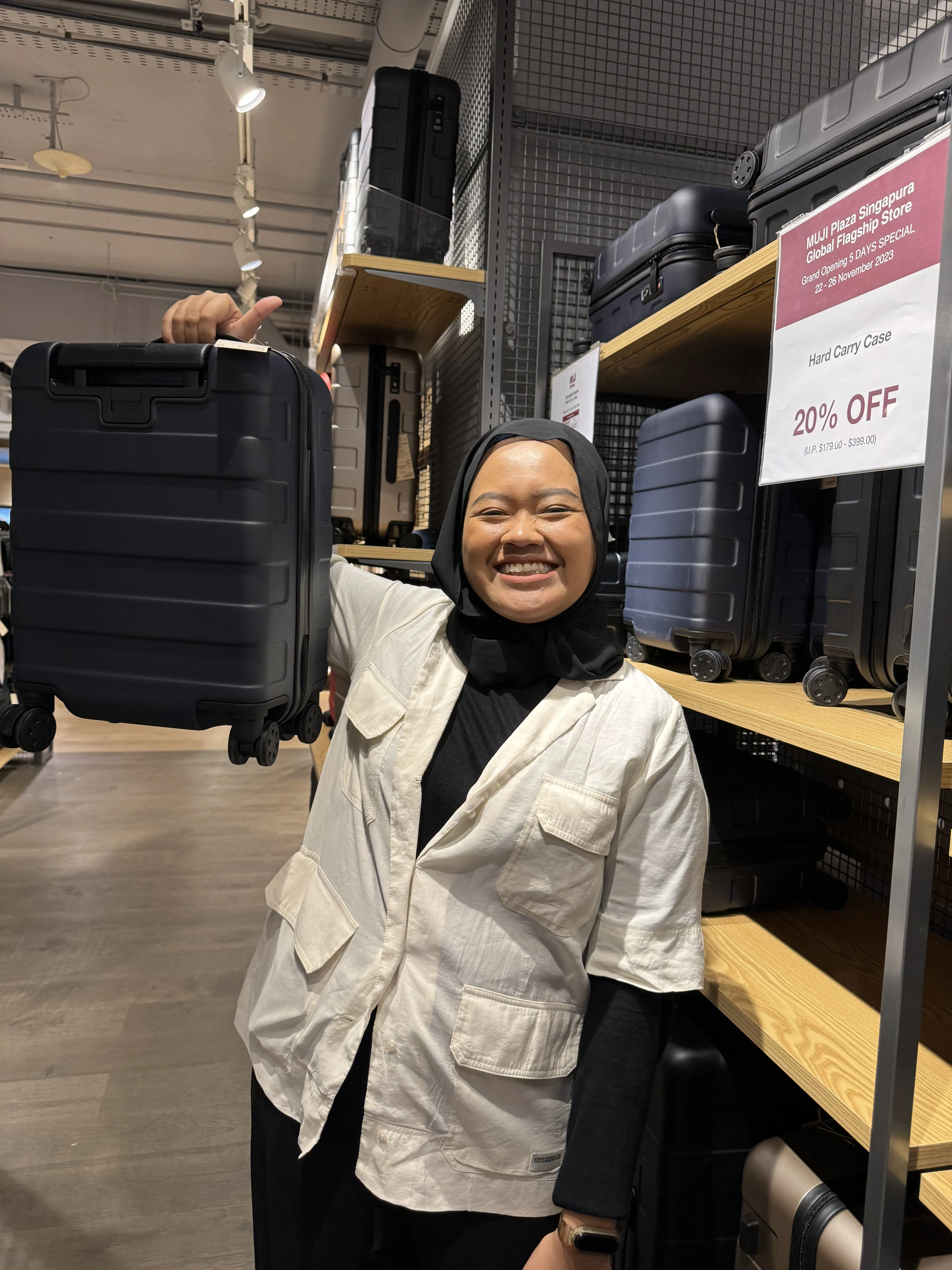 Hijabi woman holding up a luggage in MUJI