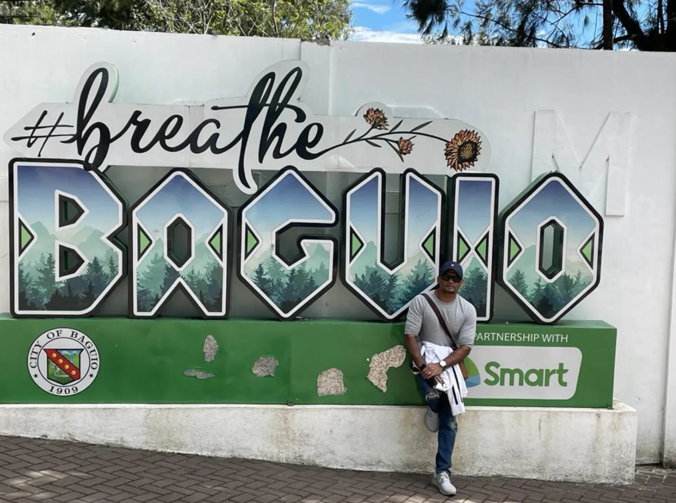 Man standing in front of Baguio sign