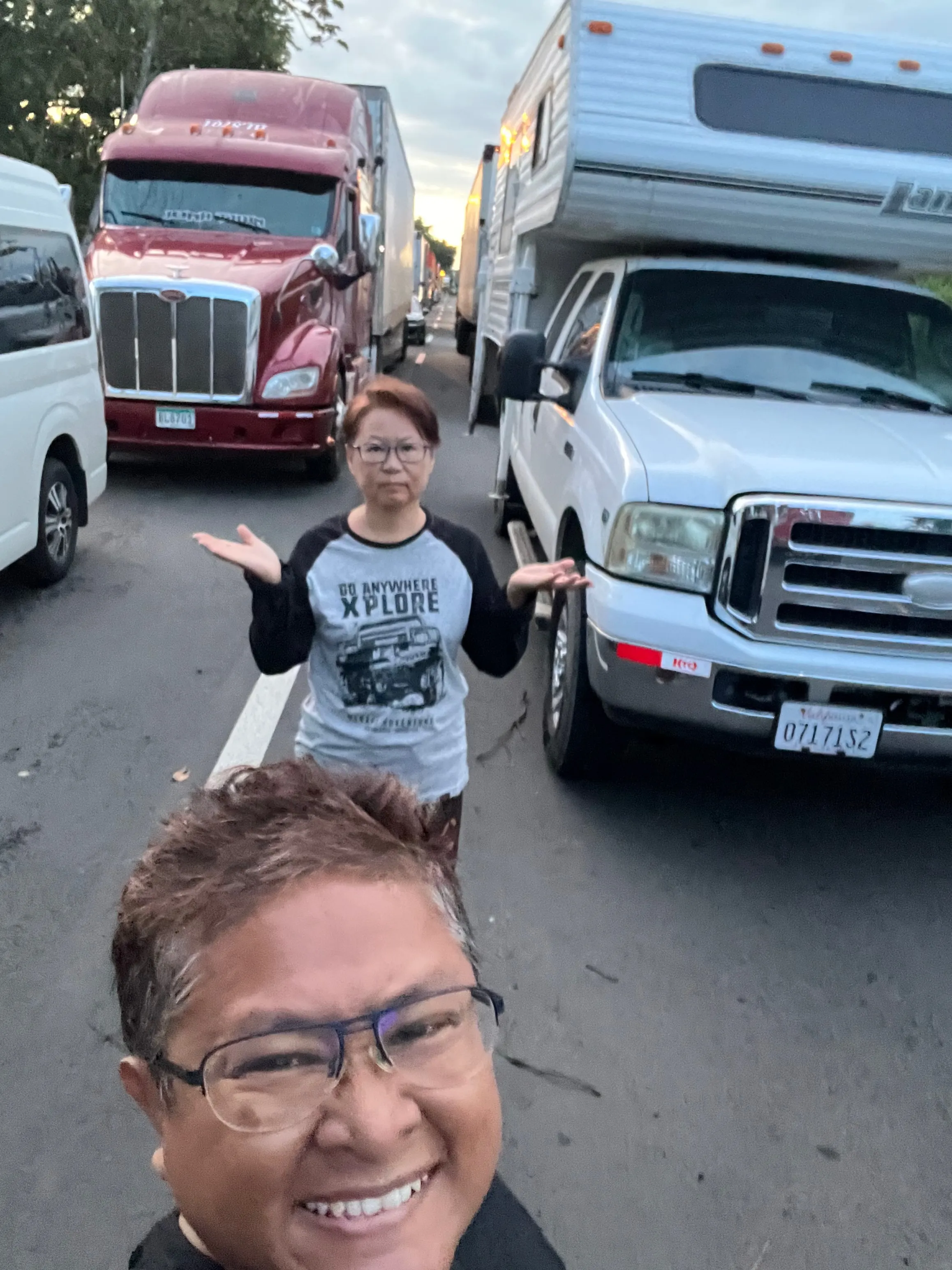 Two women taking a selfie infront of many vans on the road