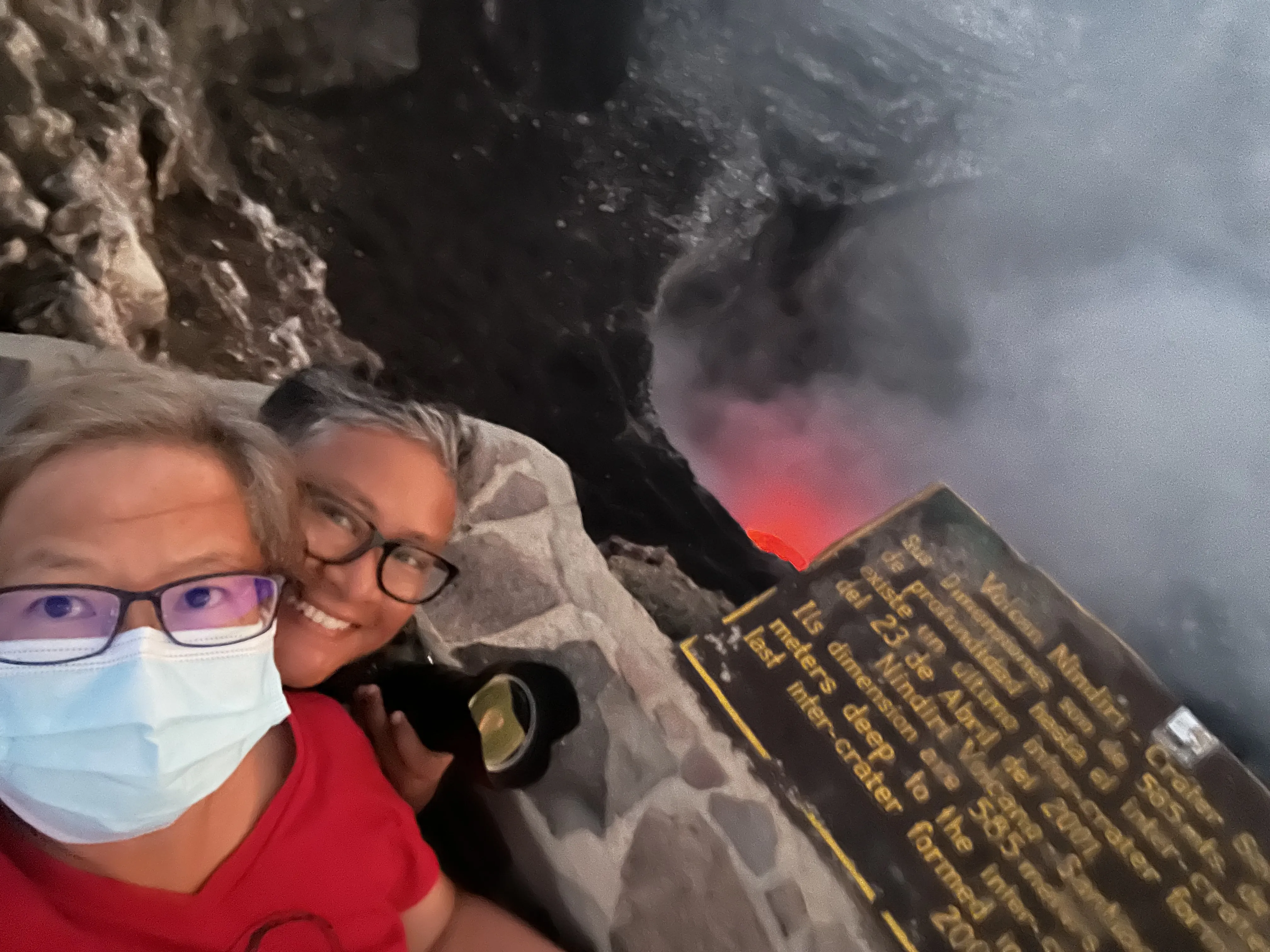 Two women posing above a crater