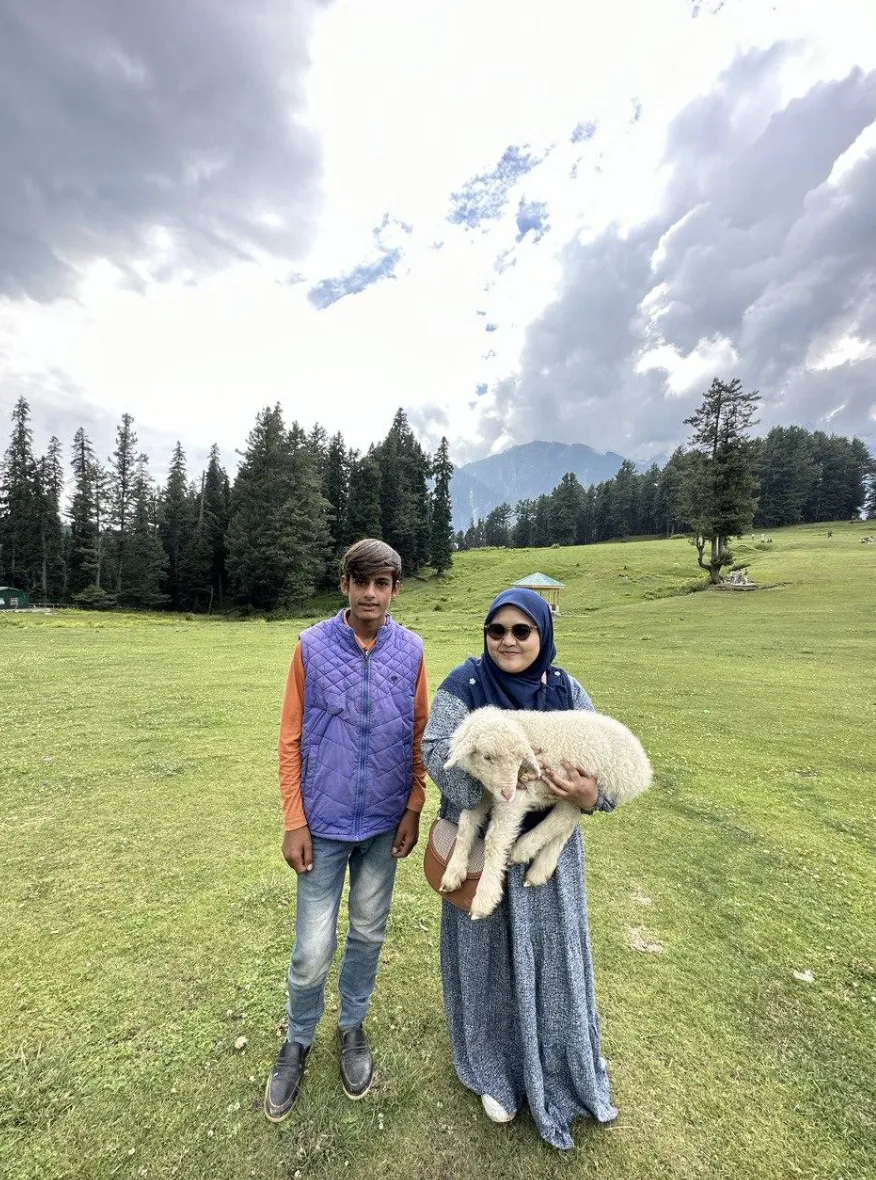 Two people at Baisaran holding a baby sheep